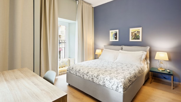 Un dormitorio con cama, mesitas de noche, un escritorio y una silla.