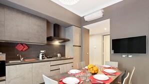 Una cocina moderna con comedor, equipada con estufa, lavamanos y televisor de pantalla plana.