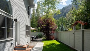 A residential backyard with a wooden deck, a small patio, and a well-maintained lawn. - Spacious, private home .6 mi from downtown Ketchum (Ketchum)