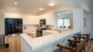 A modern kitchen with white cabinets, stainless steel appliances, and a large island with bar seating. - Spacious, private home .6 mi from downtown Ketchum (Ketchum)