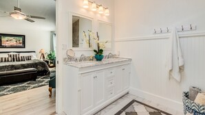Un baño con tocador blanco, un espejo grande y un perchero para toallas.