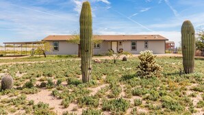Una casa con techo plano, un porche delantero y un pequeño jardín con cactus y arbustos.