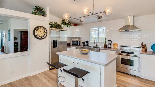 Una cocina moderna con una isla central, electrodomésticos de acero inoxidable y una lámpara colgante.