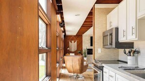 A modern kitchen with wooden cabinetry, a central island, and a hanging light fixture.