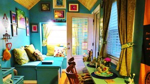 A cozy room with a blue sofa, wooden dining table, and a window with blinds.