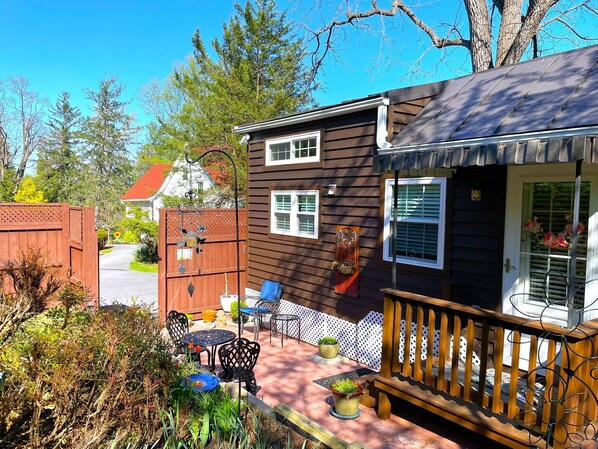 A two-story house with a porch, a small patio with outdoor furniture, and a garden area.