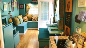 A compact kitchen with a built-in seating area, a stove, and various kitchen appliances.