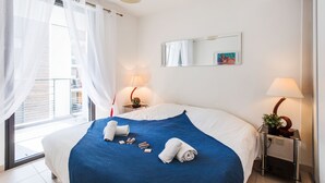 A hotel room with a large bed, a balcony with a view, a bedside table with a lamp, and a wall-mounted mirror. - VICTOR HUGO AP4159 by RIVIERA HOLIDAY HOMES (Niza)