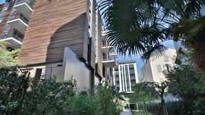 A modern building with a mix of brick and glass facades, a central courtyard with a pathway, and surrounding greenery. - VICTOR HUGO AP4159 by RIVIERA HOLIDAY HOMES (Niza)