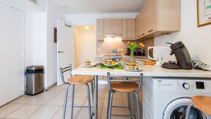 A modern kitchen with a built-in washing machine, a coffee machine, and a dining area with stools. - VICTOR HUGO AP4159 by RIVIERA HOLIDAY HOMES (Niza)