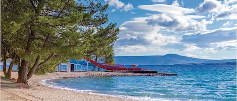 Enjoy a serene beach setting with a clear view of the sea and distant mountains.