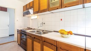 A kitchen with wooden cabinets, a gas stove, a sink, and a bowl of fruit on the counter. - Stunning home in Bakarac with house sea view (Bakarac)