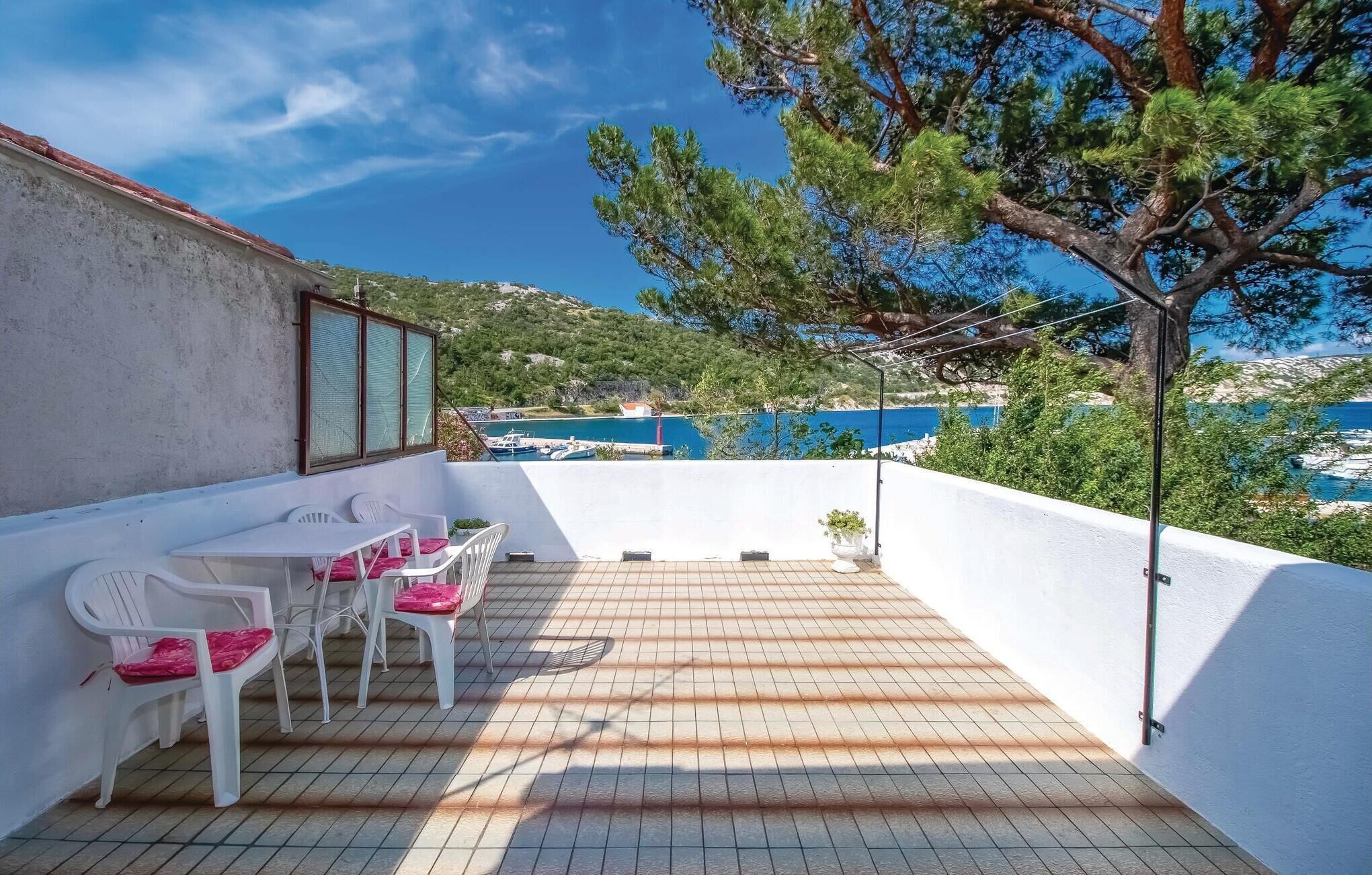 A terrace with a table and chairs, a view of the sea, and a tree.