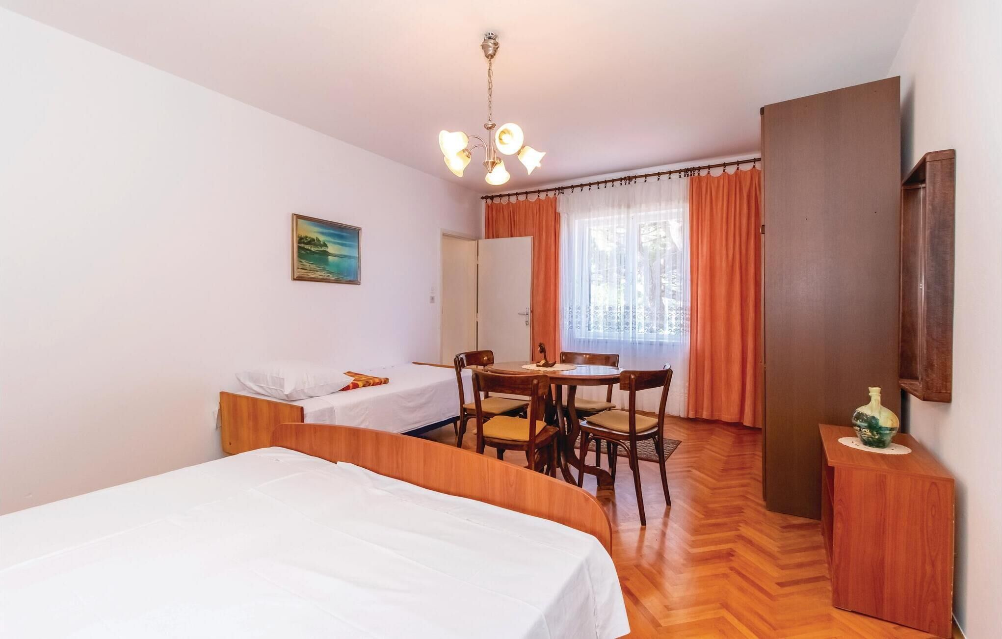 A hotel room with two beds, a dining table with chairs, a wooden cabinet, and a painting on the wall.