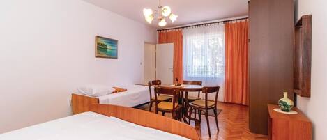 A hotel room with two beds, a dining table with chairs, a wooden cabinet, and a painting on the wall.