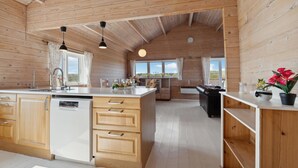A spacious kitchen with wooden cabinets, a central island, and a dining area with a black leather couch.