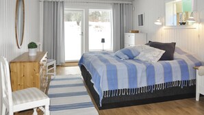 Ein Schlafzimmer mit Bett, Schreibtisch, Stuhl, Kommode und einem Fenster mit Vorhängen.