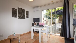 Een kamer met een eettafel, stoelen, een televisie en een schuifdeur naar buiten.