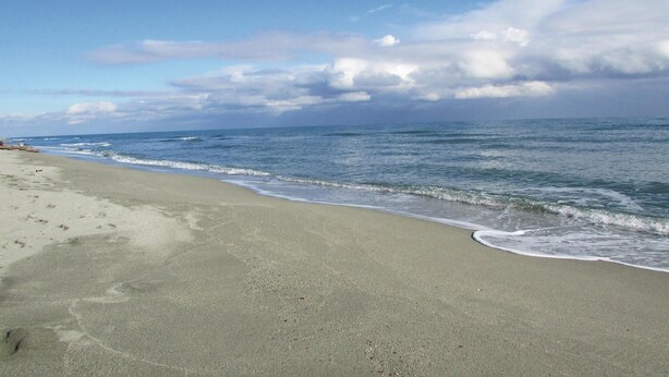 Een strand met een breed zandstrand en rustige golven.