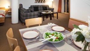 A dining area with a table set for two, a sofa, and a painting on the wall. - Chalet Abendrot apARTments by Interhome (Grindelwald)