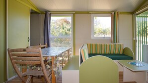 A cozy room with a wooden table, a bench with striped cushions, and a window with curtains. - 2 bedroom awesome (sta)caravan in Casalabriva (Casalabriva)