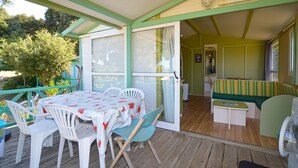 A covered patio with a table and chairs, a bench, and a door leading to an interior space. - 2 bedroom awesome (sta)caravan in Casalabriva (Casalabriva)