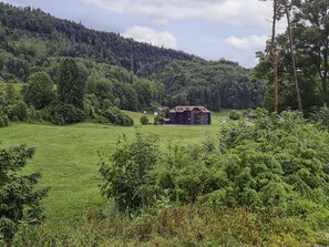 Situated in a serene rural setting, this traditional building offers a peaceful escape amidst lush green fields and dense forested hills.