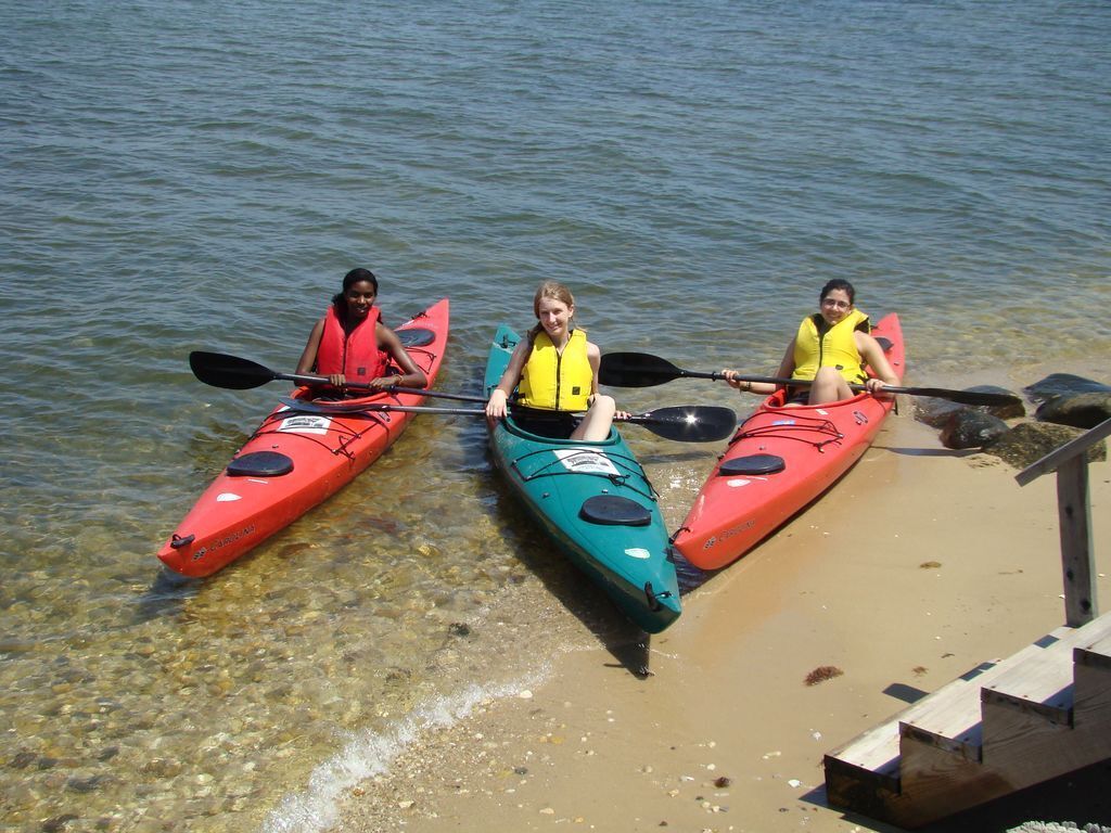 Drie kajaks op een zandstrand met helder water.
