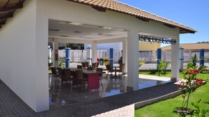 A covered outdoor dining area with a pool, surrounded by a fence and greenery. - Lacqua diRoma Hotel e Parque Aquático (Caldas Novas)