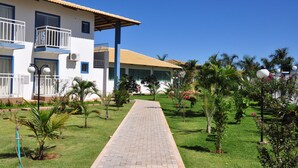 A pathway leading to a building with balconies and air conditioning units, surrounded by well-maintained greenery and palm trees. - Lacqua diRoma Hotel e Parque Aquático (Caldas Novas)