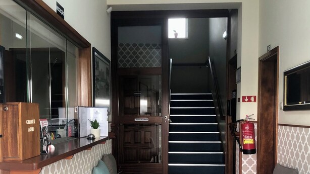 A hotel lobby with a reception desk, seating area, staircase, and a fire extinguisher. - Hotel Vila Esteves (Monção)