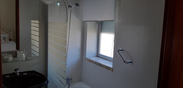 A bathroom with a glass shower enclosure, a small window, a sink, and a mirror. - Hotel Vila Esteves (Monção)