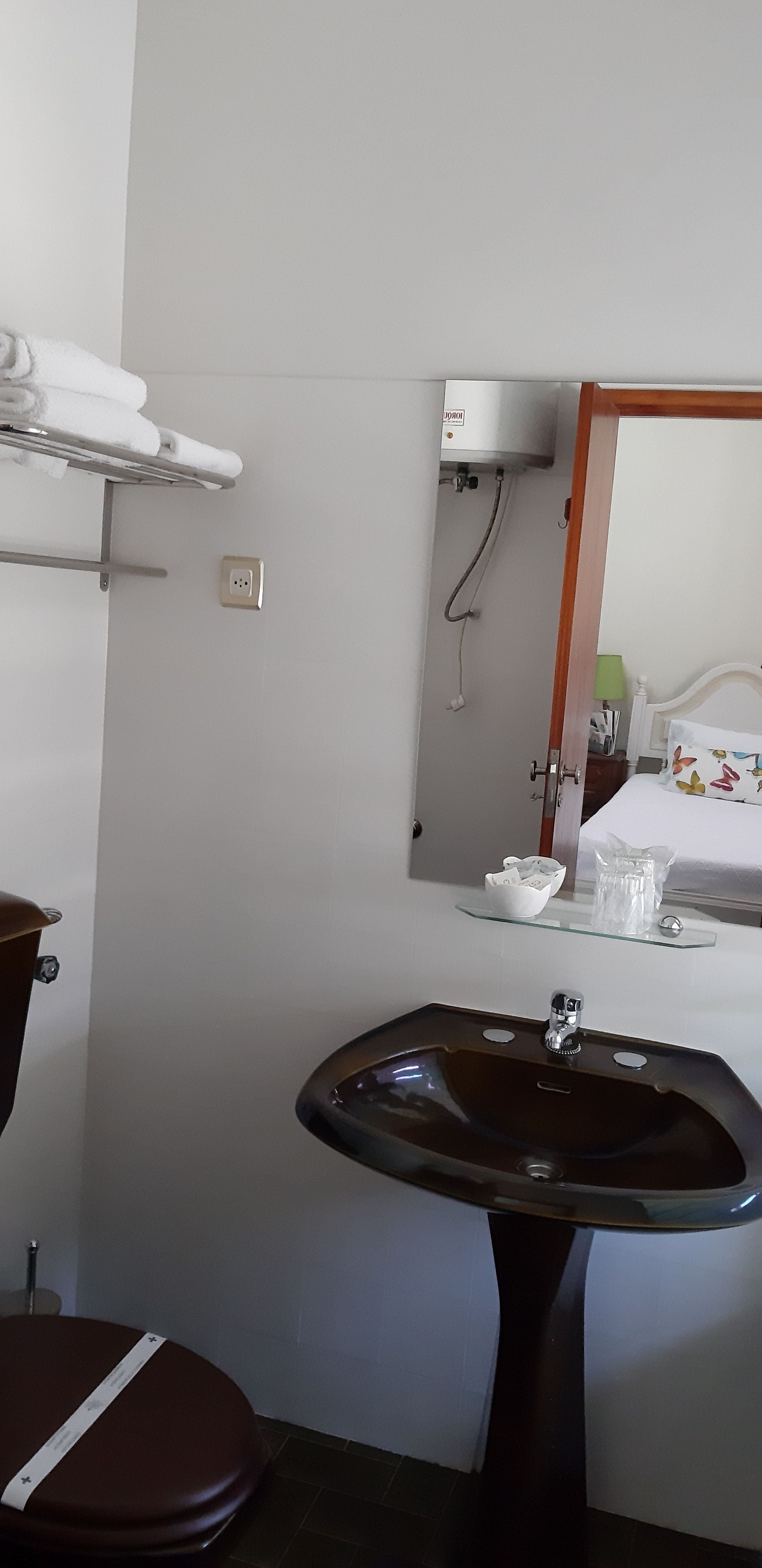 Un baño con lavamanos, inodoro y perchero para toallas.