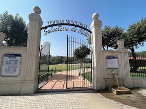 Une entrée fermée par un portail donne accès à un espace public, et une pancarte indique : « Thermes municipaux Salvatore de Miza ».