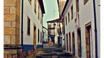 Una calle estrecha con pavimento de piedra, edificios blancos con numerosas ventanas y un farol tradicional.