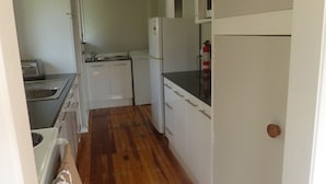A compact kitchen with white cabinets, a sink, a toaster, a refrigerator, and a microwave. - Take time out in Turangi - family friendly (Turangi)