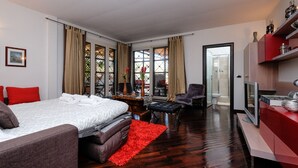 Et moderne hotelværelse med en stor seng, et skrivebord, en stol og et fjernsyn.