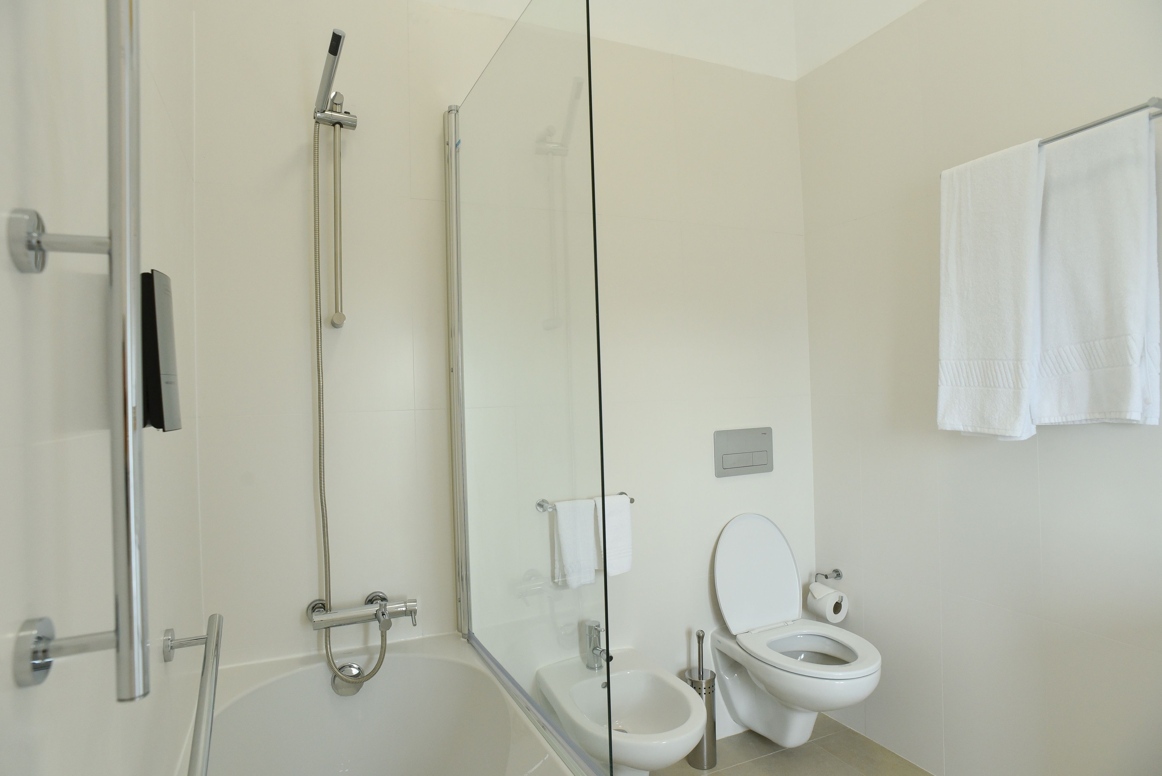 A modern bathroom with a glass shower enclosure, a bathtub, a toilet, and a bidet.