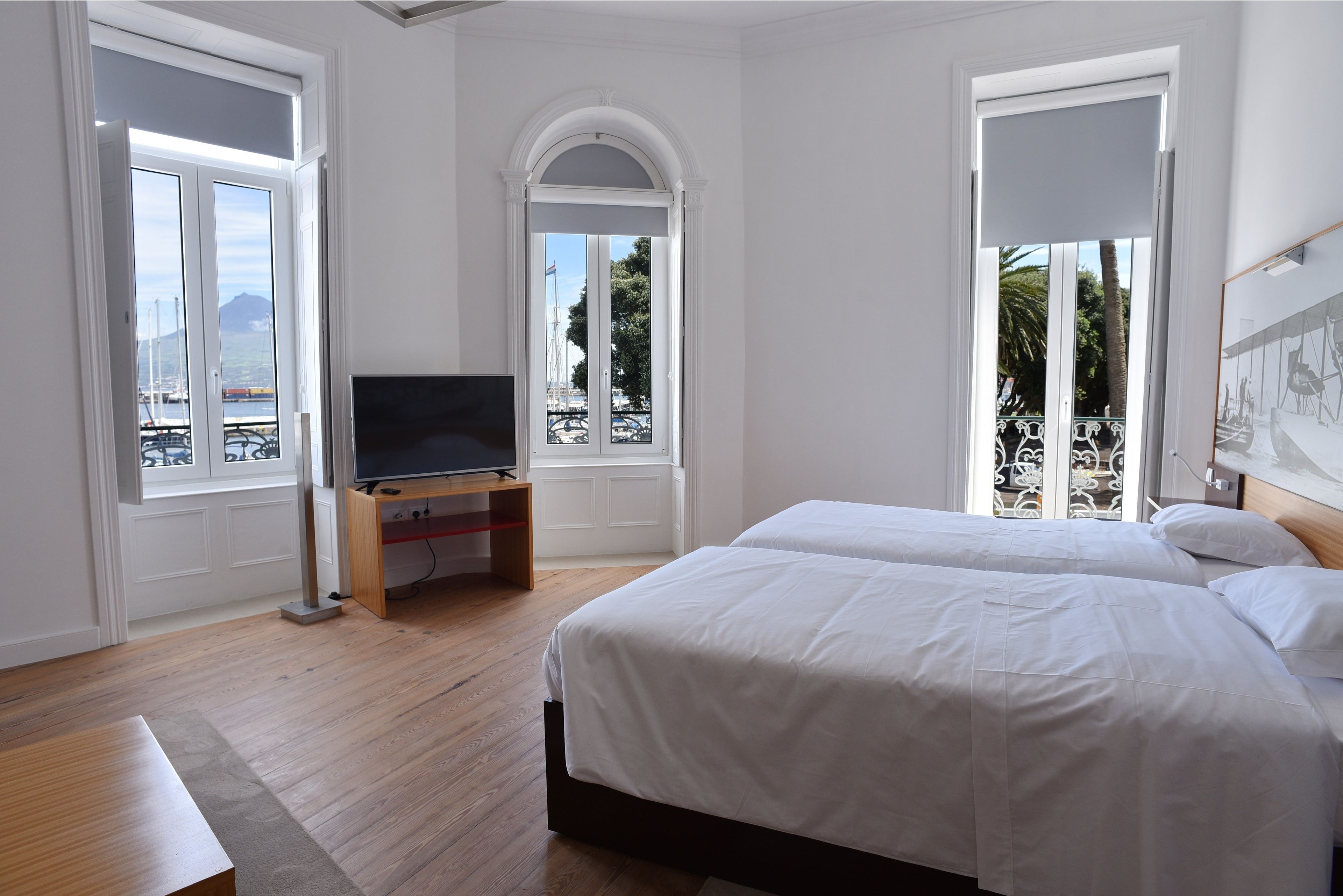 Une chambre d’hôtel avec un lit, un téléviseur posé sur un meuble et de grandes fenêtres donnant sur la mer.