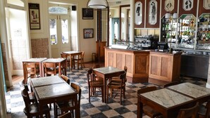 A restaurant with checkered flooring, wooden tables and chairs, a bar area, and framed pictures on the walls. - Internacional Azores Boutique (Horta)