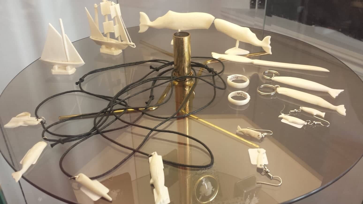 Une exposition de divers petits objets blancs, ressemblant à des maquettes, sur une table en verre.