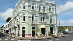 A historic building with a green facade, multiple balconies, and a prominent entrance. - Internacional Azores Boutique (Horta)