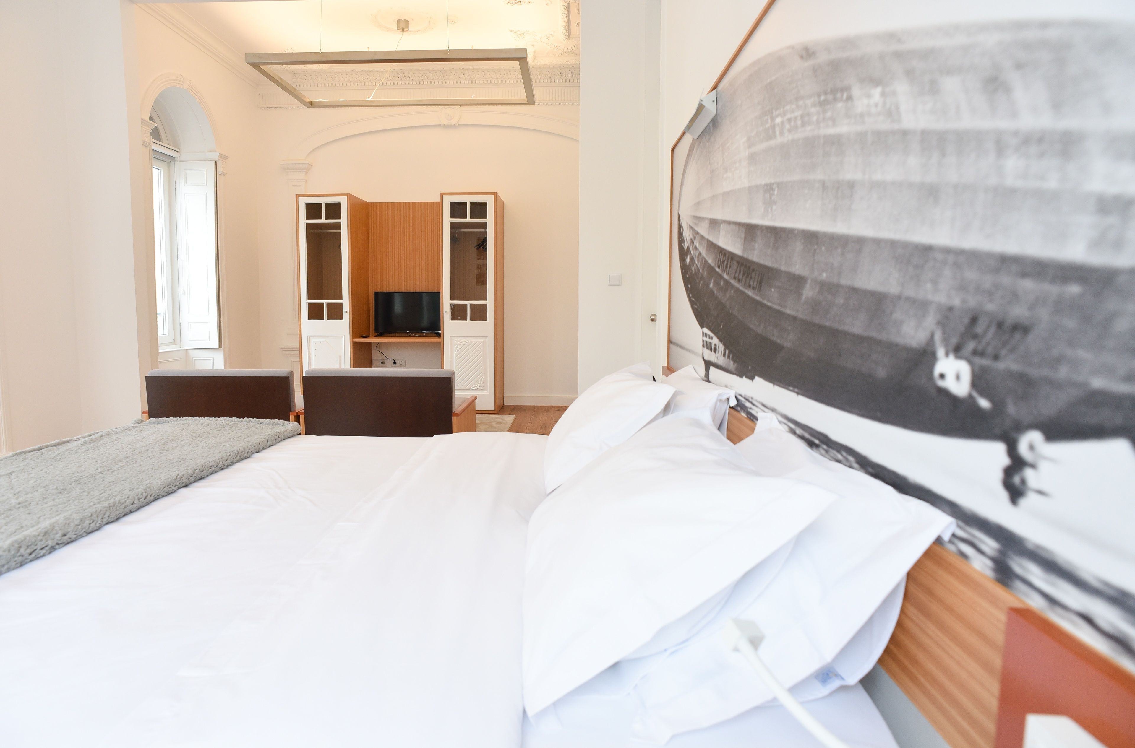 Habitación de hotel con una cama grande, televisor, armario y un cuadro en la pared.