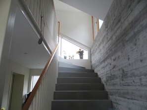 Un escalier avec une rampe en bois menant à un palier d’où l’on peut admirer la vue sur l’extérieur.