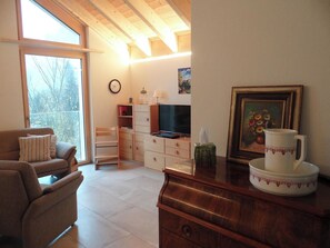 Un salon comprenant un canapé, un téléviseur, des meubles en bois et une grande fenêtre.