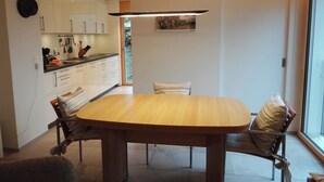 A modern kitchen with white cabinets, a wooden dining table, and chairs.