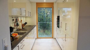 A modern kitchen with white cabinets, a black countertop, and a window with a view of trees.