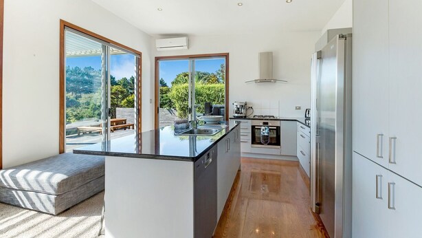 Una cocina moderna con una isla central, electrodomésticos de acero inoxidable y grandes ventanales con vistas al exterior.