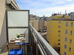 A balcony with a table set for two, overlooking a cityscape with yellow buildings. - Vienna waits for you by Interhome (Vienna / 5. District)