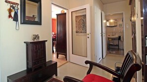 A living room with a dark wooden cabinet, a red chair, and a mirror on the wall. A door leads to a bathroom with a sink and mirror. - Vienna waits for you by Interhome (Vienna / 5. District)